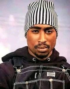 a man wearing a black and white hat with stripes on it's head, standing in front of a gray background