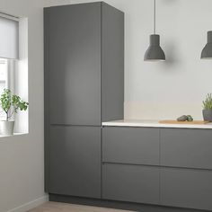 a kitchen with grey cabinets and plants in the window sill, along with two hanging lights