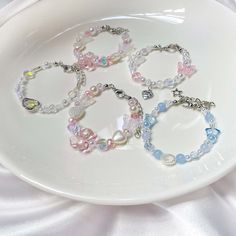 four bracelets with charms on a white plate