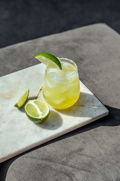 a drink on a marble tray with limes