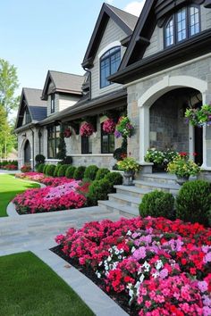 a house with many flowers in the front yard and landscaping on both sides of it