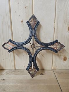 a decorative metal cross hanging on the side of a wooden wall