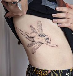 a woman with a humming tattoo on her stomach holding onto the side of her body