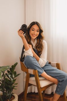 a woman sitting in a chair holding a hair dryer