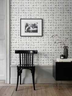 a black chair sitting in front of a wall with a painting on it's side