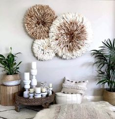 three large circular wall hangings on the wall above a table with candles and plants