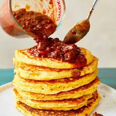 stack of pancakes with sauce being poured on top