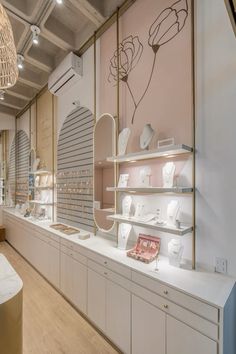 the interior of a store with white shelves and vases on display in front of them