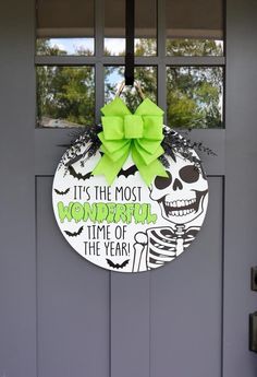 a door hanger with a green bow hanging from it's side, decorated with a skeleton