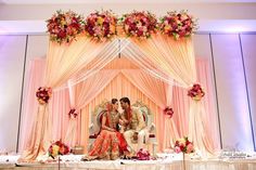 two people sitting on a couch in front of a wedding arch