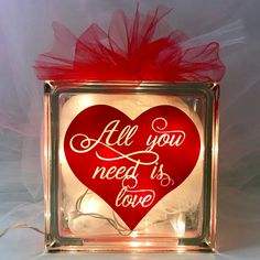 a red heart with the words all you need is love on it in a glass block