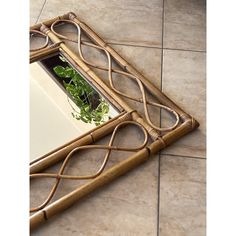 a mirror sitting on top of a tiled floor next to a potted green plant