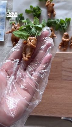 a hand holding a plastic bag filled with small figurines on top of a table