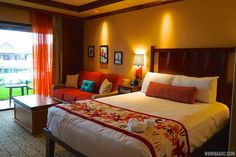 a bed room with a neatly made bed next to a large window and a chair