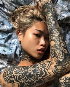 a woman laying on top of a bed covered in tattoos