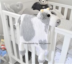 a crocheted cow blanket hanging from the side of a crib