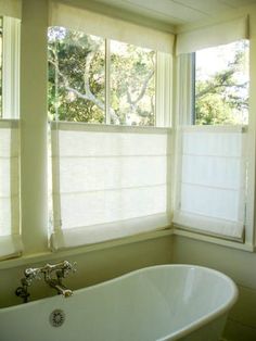 a white bath tub sitting under two windows