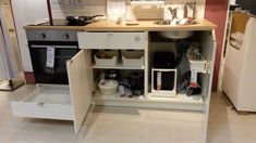 an open cabinet in the middle of a kitchen