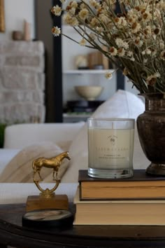 a vase with flowers and a candle sitting on a table next to a stack of books