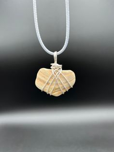 a white necklace with a wooden heart on it's side and two strings hanging from the front