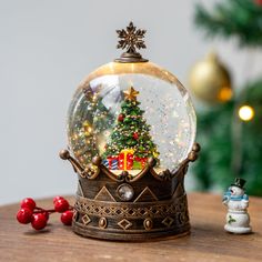 a snow globe sitting on top of a wooden table next to a small christmas tree