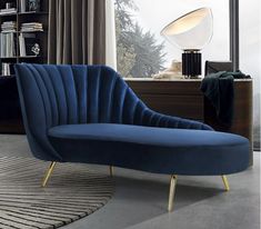 a green chair sitting in front of a window next to a book shelf and lamp