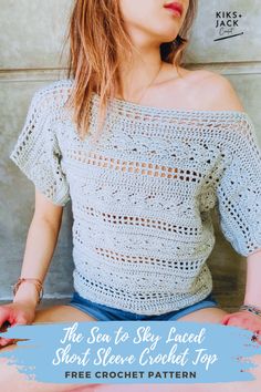 a woman sitting on the ground with her hands in her pockets, wearing a crochet top