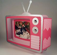 a small pink tv with a dog on it's side and a christmas tree in the background