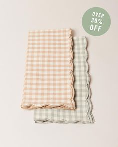 two gingham napkins with scalloped edges on white background, one in pink and the other in green