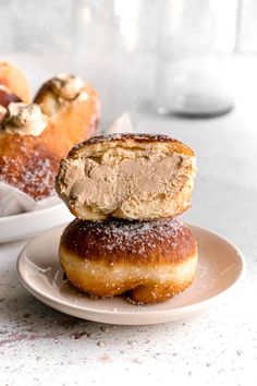 two doughnuts sitting on top of each other in front of a bowl filled with powdered sugar