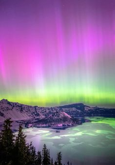 the aurora bore is seen over a lake and mountains