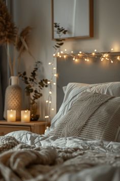 an unmade bed with white sheets and lights on the headboard in front of it