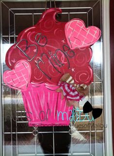 a cupcake decorated with hearts and the word happy on it is hanging in front of a window