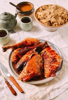 there is a plate with chicken and rice next to two mugs on the table