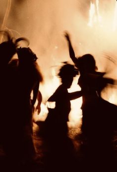 two people dancing in front of a fire