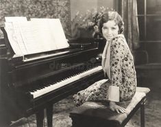 an old photo of a woman sitting at a piano