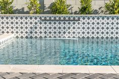 an empty swimming pool with tiled walls and blue water