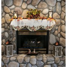 a stone fireplace with a white table cloth over the mantel and two lanterns on each side