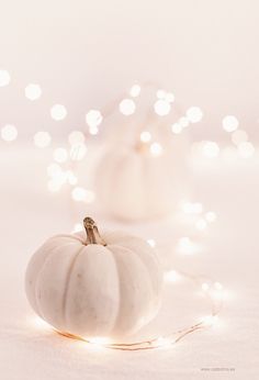 a white pumpkin sitting on top of a table next to a string of christmas lights