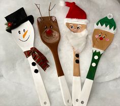 four wooden spoons decorated like santa claus, snowman, and reindeer faces with fake noses