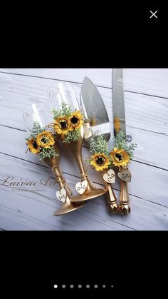 three sunflowers are placed in gold vases with knives and flowers on them