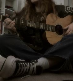 a man sitting on the floor playing an acoustic guitar