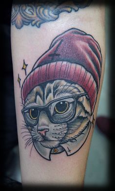 a cat with glasses and a hat on it's head is shown in this tattoo