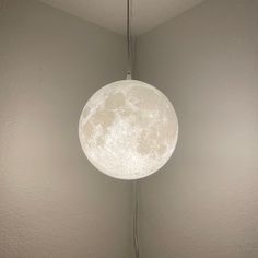 a white lamp hanging from the ceiling in a room with grey walls and flooring