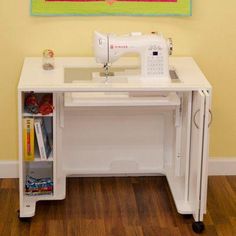 a sewing machine sitting on top of a white table next to a wall with a painting