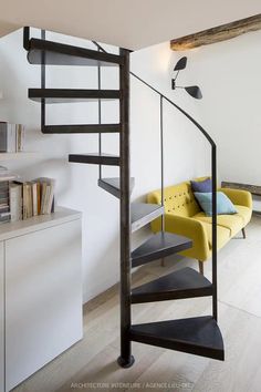 a living room with a yellow couch and a spiral stair case in it's center