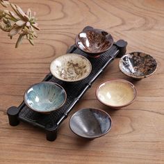 four bowls are sitting on a black stand with one bowl in the middle and two empty ones