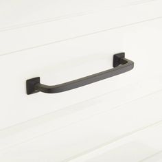 an image of a black handle on a white cabinet door that is painted in dark gray