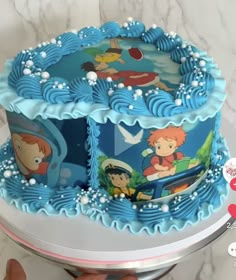 someone is holding up a cake decorated with cartoon characters on the frosting and blue icing