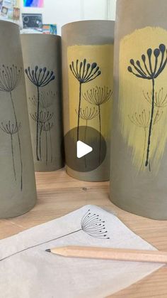 some vases are sitting on a table with pencils and paper in front of them